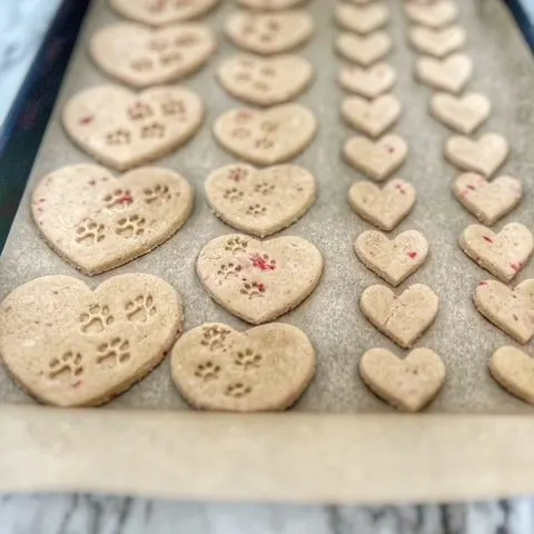 strawberry banana heart-shaped dog treats on a baking sheet